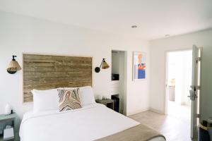 a bedroom with a white bed with a wooden headboard at SCP Seven4One Hotel in Laguna Beach