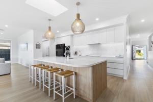 a kitchen with a white counter and stools at Osprey Oasis in Banksia Beach