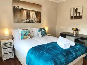 ein Schlafzimmer mit einem Bett mit einer blauen Decke darauf in der Unterkunft Riverside 4 Bedroom House Wraysbury Staines in Wraysbury