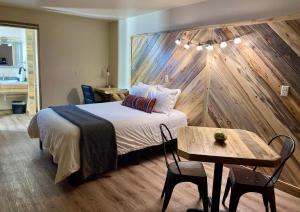 1 dormitorio con 1 cama con pared de madera en Horseshoe Bend Motel en Lovell