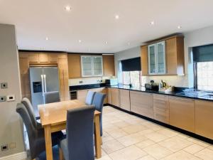eine große Küche mit einem Holztisch und Stühlen in der Unterkunft Riverside 4 Bedroom House Wraysbury Staines in Wraysbury