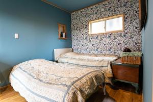 2 łóżka w pokoju z niebieskimi ścianami w obiekcie 鉢巻山荘 w mieście Omura