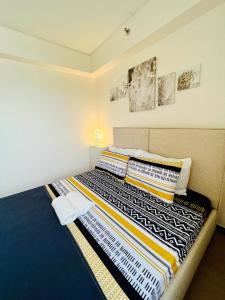 1 dormitorio con 1 cama con mantas y almohadas coloridas en The Celandine A Bonifacio Balintawak Condotel en Manila