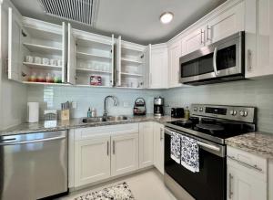 a kitchen with white cabinets and black appliances at Modern Townhouse with terrace! in Homestead