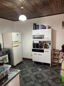 La cuisine est équipée d'un réfrigérateur blanc et d'un four micro-ondes. dans l'établissement El mochilero, à Cartago