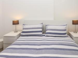 una camera da letto con un letto con cuscini a righe blu e bianche di Sea Aster a Teignmouth