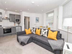 a living room with a gray couch and yellow pillows at Beach Rose in Teignmouth