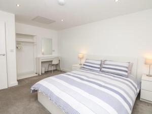 a white bedroom with a bed and a desk at Beach Rose in Teignmouth