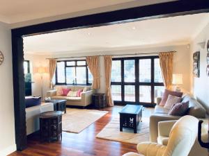 Una sala de estar con sofás, mesas y ventanas. en Riverside 4 Bedroom House Wraysbury Staines, en Wraysbury