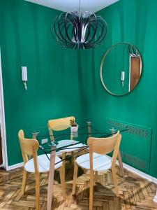 un comedor verde con mesa de cristal y sillas en Iluminada Haus en Buenos Aires