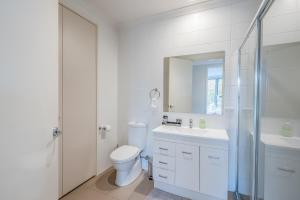 a white bathroom with a toilet and a sink at One Bedroom Apartment in Braddon in Canberra
