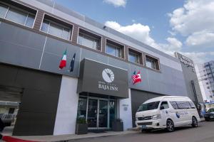 una furgoneta blanca estacionada frente a un edificio en Baja Inn Hoteles La Mesa en Tijuana