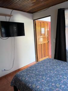 una camera con letto, televisore e porta di El mochilero a Cartago