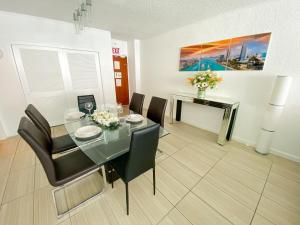 a dining room with a glass table and black chairs at Oceanfront Condo - Ocean Views, Pool, Gym Hollywood Beach in Hollywood