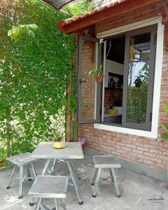 Homestay Mộc Nhi في هوى: طاولة نزهة وكرسيين أمام المنزل