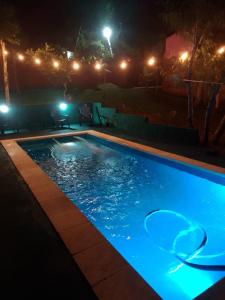 uma piscina iluminada à noite com luzes em Cabañas cerella em Puerto Iguazú
