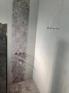 a bathroom with a shower with a stone wall at Dormis:Lodesilvi in Merlo