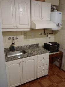 uma cozinha com armários brancos e um lavatório em Departamento Lorenzo I em Mendoza