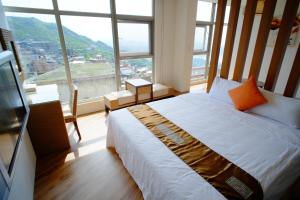 a bedroom with a bed and a large window at Chiu Chunt Dint B&B in Jiufen