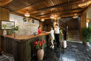 a man and woman standing at a bar in a restaurant at Sin Chai Ecolodge in Sa Pa