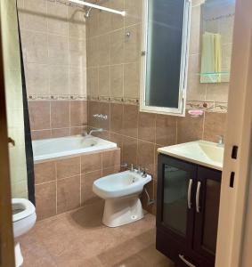 a bathroom with a toilet and a tub and a sink at Depto cómodo, ubicación perfecta in Pergamino