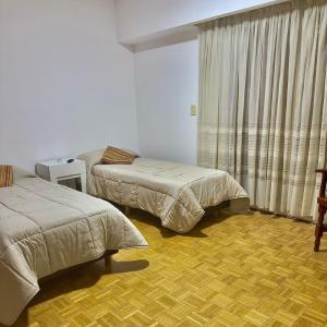a hotel room with two beds and a window at Depto cómodo, ubicación perfecta in Pergamino