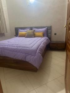 un letto con lenzuola e cuscini viola in una stanza di Appartement centre-ville a Fes