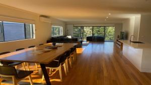 Il dispose d'une cuisine et d'un salon avec une table et des chaises en bois. dans l'établissement Lakewood Drive Merimbula, à Merimbula