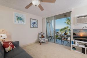 a living room with a couch and a tv at Kailua Village 5th floor - View of Kailua Bay KV506 in Kailua-Kona