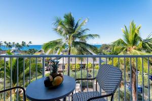 a table and chairs on a balcony with palm trees at Kailua Village 5th floor - View of Kailua Bay KV506 in Kailua-Kona