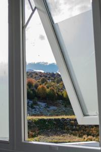 una ventana en una casa con vistas a los árboles en Altos de Cervantes, en Ushuaia 2 fotos más