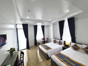 a hotel room with two beds and a desk at Seaside Hotel - Rach Gia in Rạch Giá