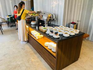 a woman standing at a buffet with plates of food at Liberty Hotel Saigon Greenview in Ho Chi Minh City