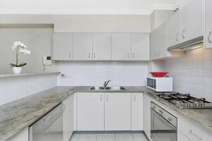 a white kitchen with a sink and a microwave at BAR09- 1 bedroom unit In Heart of Cremorne in Sydney