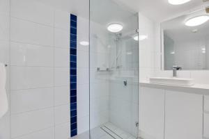 een witte badkamer met een douche en een wastafel bij Apartment on Top of the Park in Sydney
