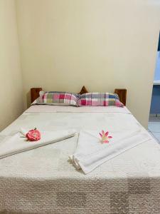 a bed with white towels and pink flowers on it at Recanto do paraiso in Itacaré