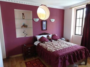 Un dormitorio con una pared púrpura y una cama en Hostal San Juan, en Quito