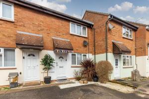 a brick house with white doors on a street at iStay Here Ltd - Luxury 1 Bed with Wifi, Sky, Parking - African Adventure in Aston End