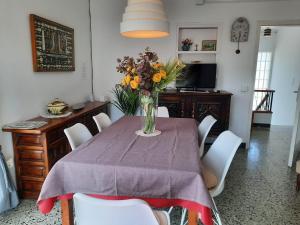 a dining room table with a vase of flowers on it at CASA FERRER - Casa grande de ambiente familiar en Llançà, cerca de la playa y del puerto.. - ES-228-64 in Llança