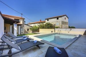 a swimming pool with lounge chairs next to a house at Villa Villetta Valtura in Ližnjan