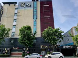 due auto parcheggiate di fronte a un edificio di Fox Motel a Daegu