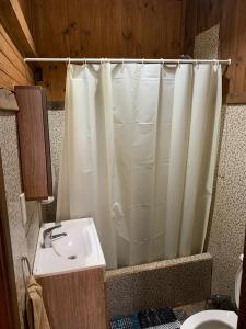 a bathroom with a shower curtain and a sink at Los Bananos - Big Wood Cabin in Puerto Iguazú