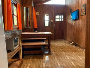 Zimmer mit einem Tisch und einem TV in einem Haus in der Unterkunft Los Bananos - Big Wood Cabin in Puerto Iguazú