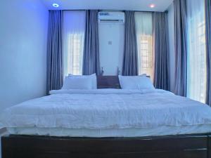 sypialnia z dużym łóżkiem z niebieskimi ścianami i oknami w obiekcie Vacvilla Shortlets 
