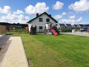 a house with a yard with a playground and a house at Cozy family cottages, not far from the sandy beach, in a quiet location, Gaski in Gąski