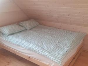 a bed in a wooden room with two pillows on it at Cozy family cottages, not far from the sandy beach, in a quiet location, Gaski in Gąski