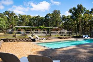 uma piscina com cadeiras e uma casa em 6 bedroom 30 acre luxury daylesford retreat em Glenlyon