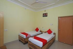 una camera con 2 letti con cuscini rossi di OYO Hotel Kanako International a Bodh Gaya