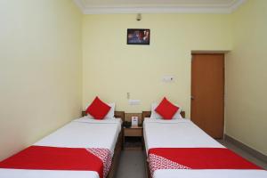 2 letti in una camera con cuscini rossi di OYO Hotel Kanako International a Bodh Gaya