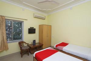 1 dormitorio con 2 camas, silla y ventana en OYO Hotel Kanako International, en Bodh Gaya